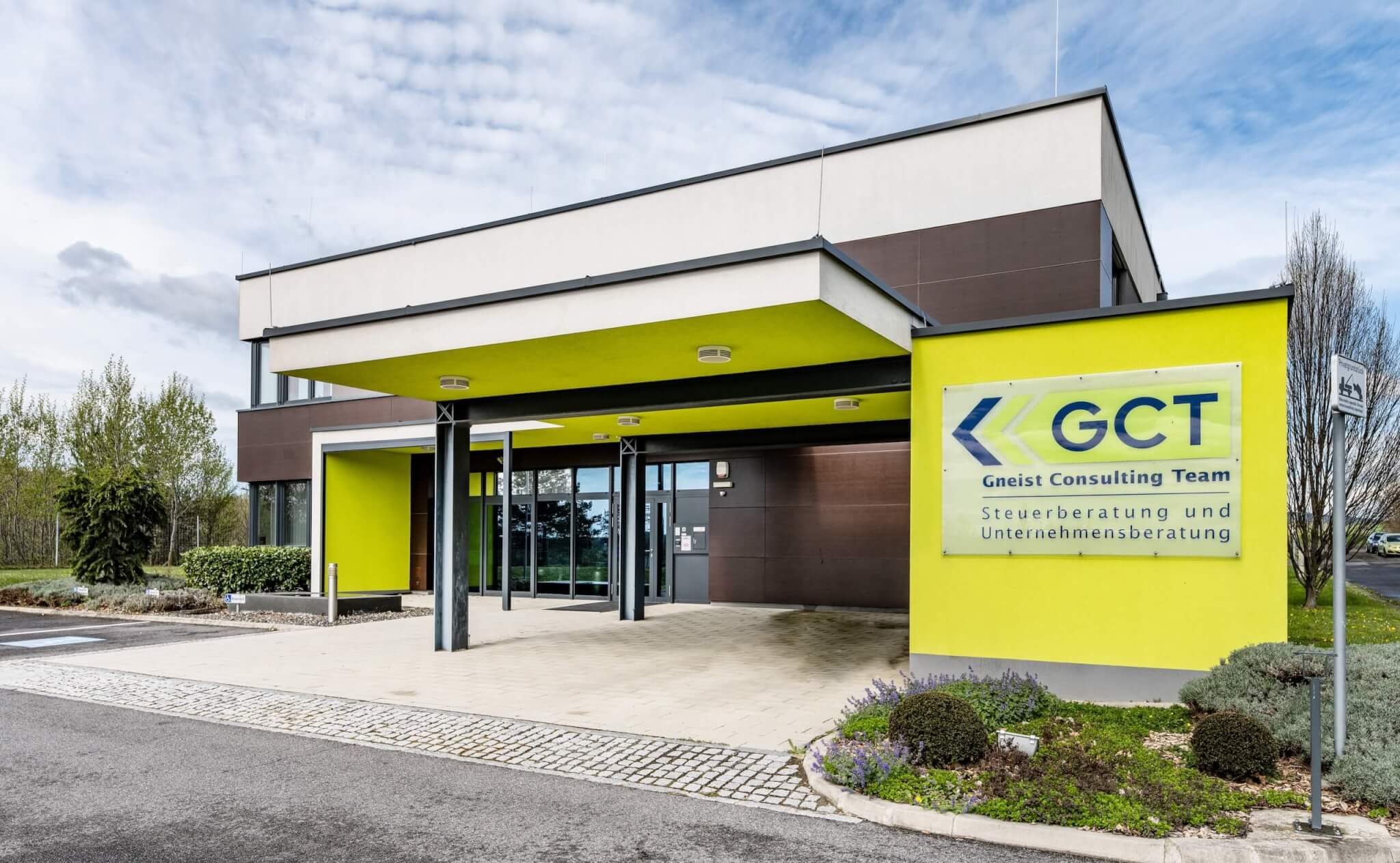 Moderne Fassade von GCT, spezialisiert auf Steuerberatung und Unternehmensberatung, mit grünem Eingang und klarer Beschilderung.