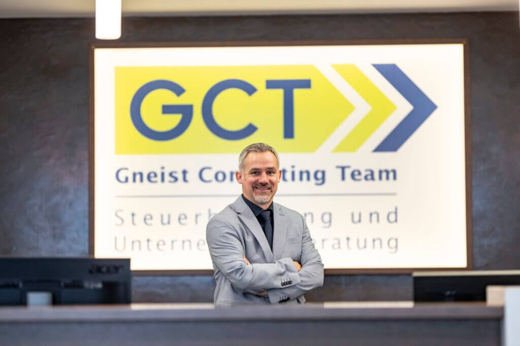 BMD Fachbereichsleiter Mag. (FH) Peter Tremmel steht mit verschränkten Armen vor dem GCT Logo.