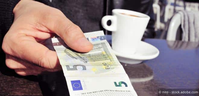 5-Euro-Schein als Trinkgeld in einem Kaffeehaus auf dem Tisch als Symbol für die Trinkgeldpauschale.