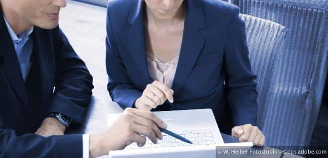 Mann berät eine Frau mit Stift und Block im Rahmen der Offenlegungspflicht.