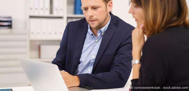 Ein Mann und eine Frau schauen gemeinsam in einen Laptop, was sinnbildlich für die Risiken und Prüfungen rund um ein Scheinunternehmen steht.