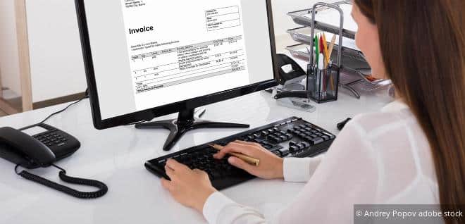 Frau bearbeitet eine Rechnung am Computer – Symbol für Rechnungsberichtigung und korrekte Buchführung.