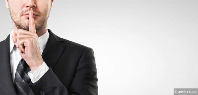 Person macht eine „Ruhe bitte“-Gestik – Symbol für Steuergeheimnis und vertrauliche Finanzdaten.