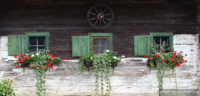 Bäuerliches Haus mit Blumen am Fensterbrett – Symbol für landwirtschaftliche Nebentätigkeiten und Zusatzangebote am Hof.